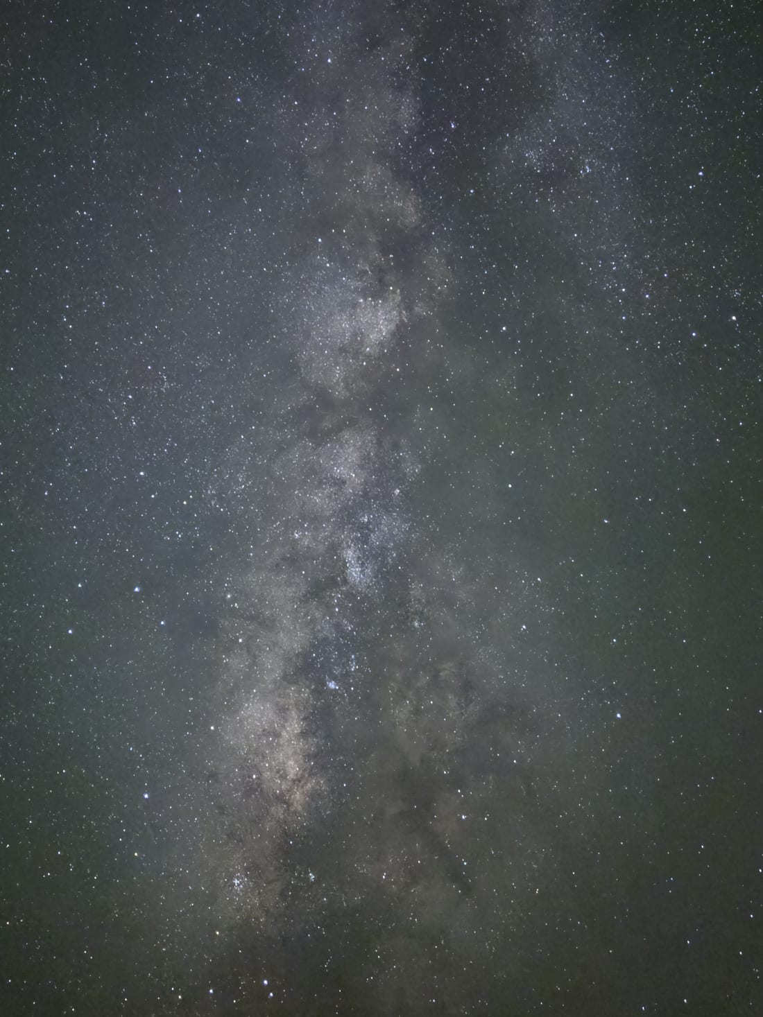 A single unedited Milky Way frame: faint, flat, green-tinted and noisy, with light-pollution glow filling the sky.